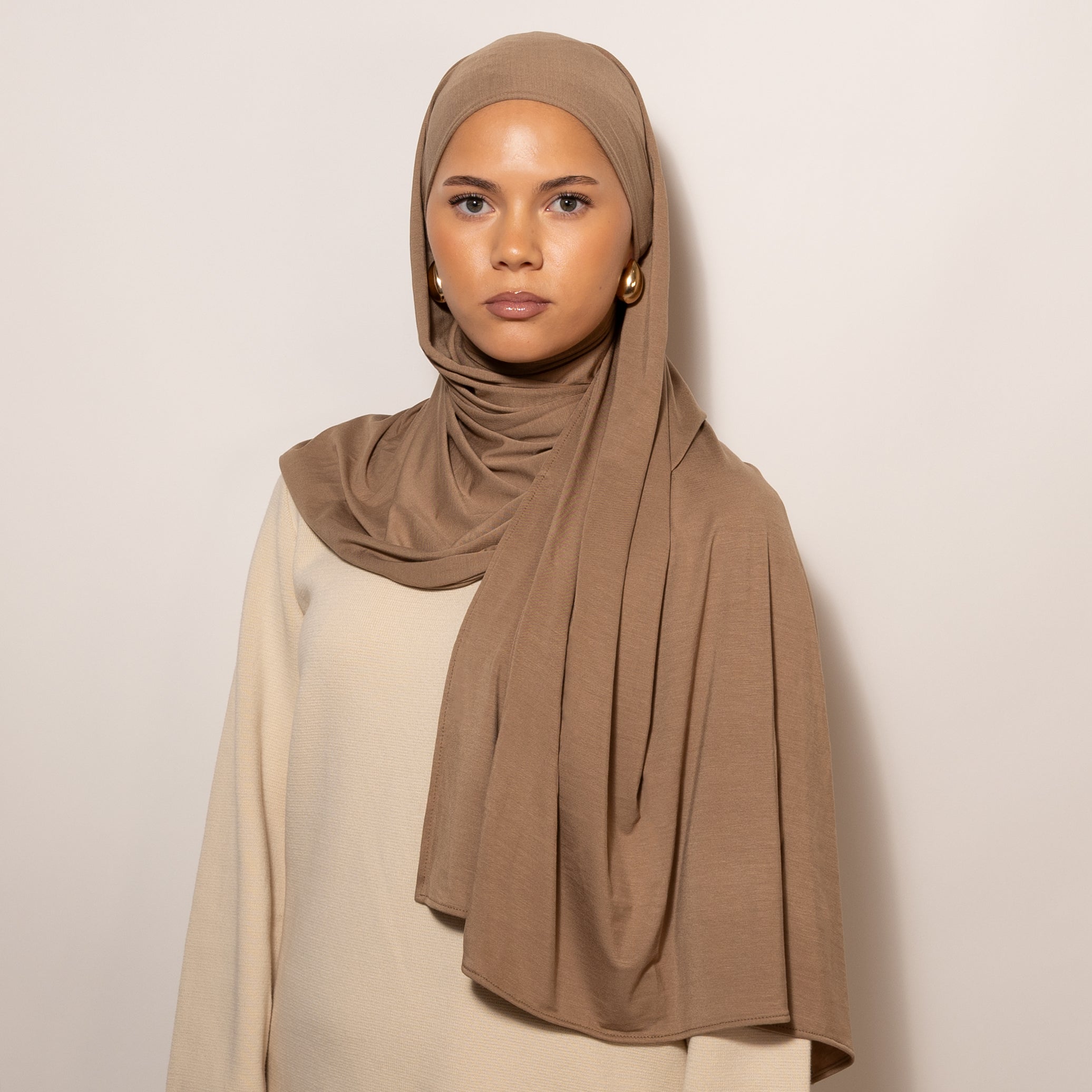 Nainen puettuna tyylikkäästi Bamboo Jersey Deep Sand Hijab huiviin
